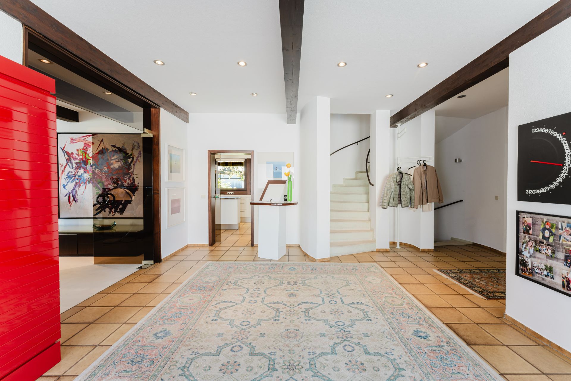 Großer Flur mit Teppich, Kunstwerken an den Wänden und einer Treppe im Hintergrund.