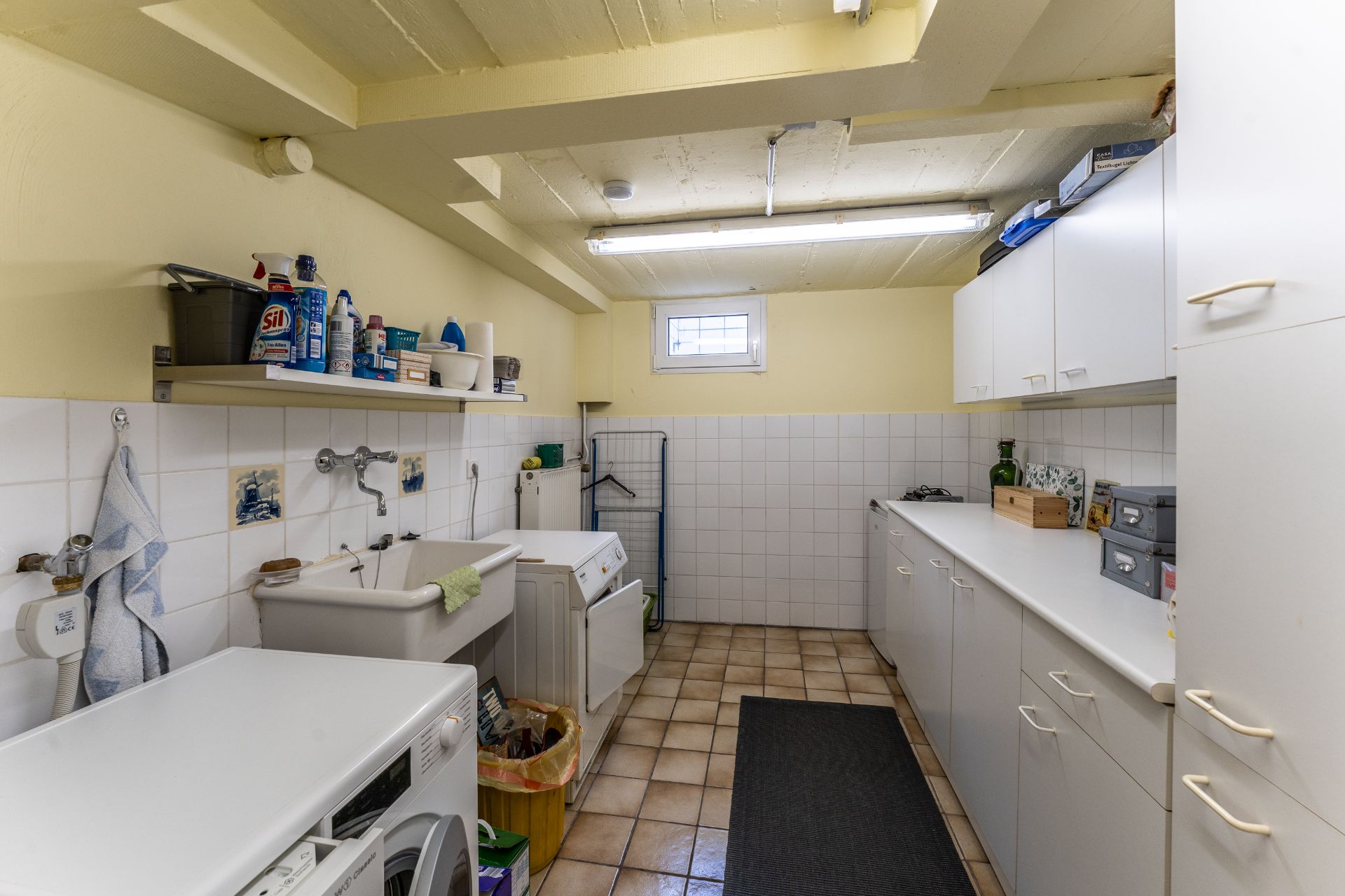 Hauswirtschaftsraum mit Waschmaschine, Trockner, Spüle und weißen Einbauschränken.