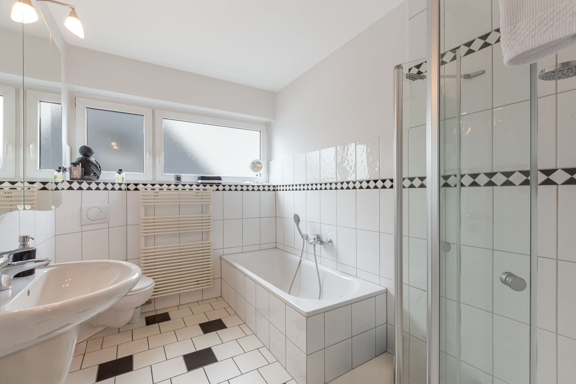 Helles Badezimmer mit Badewanne, Dusche, Waschbecken und großem Fenster.