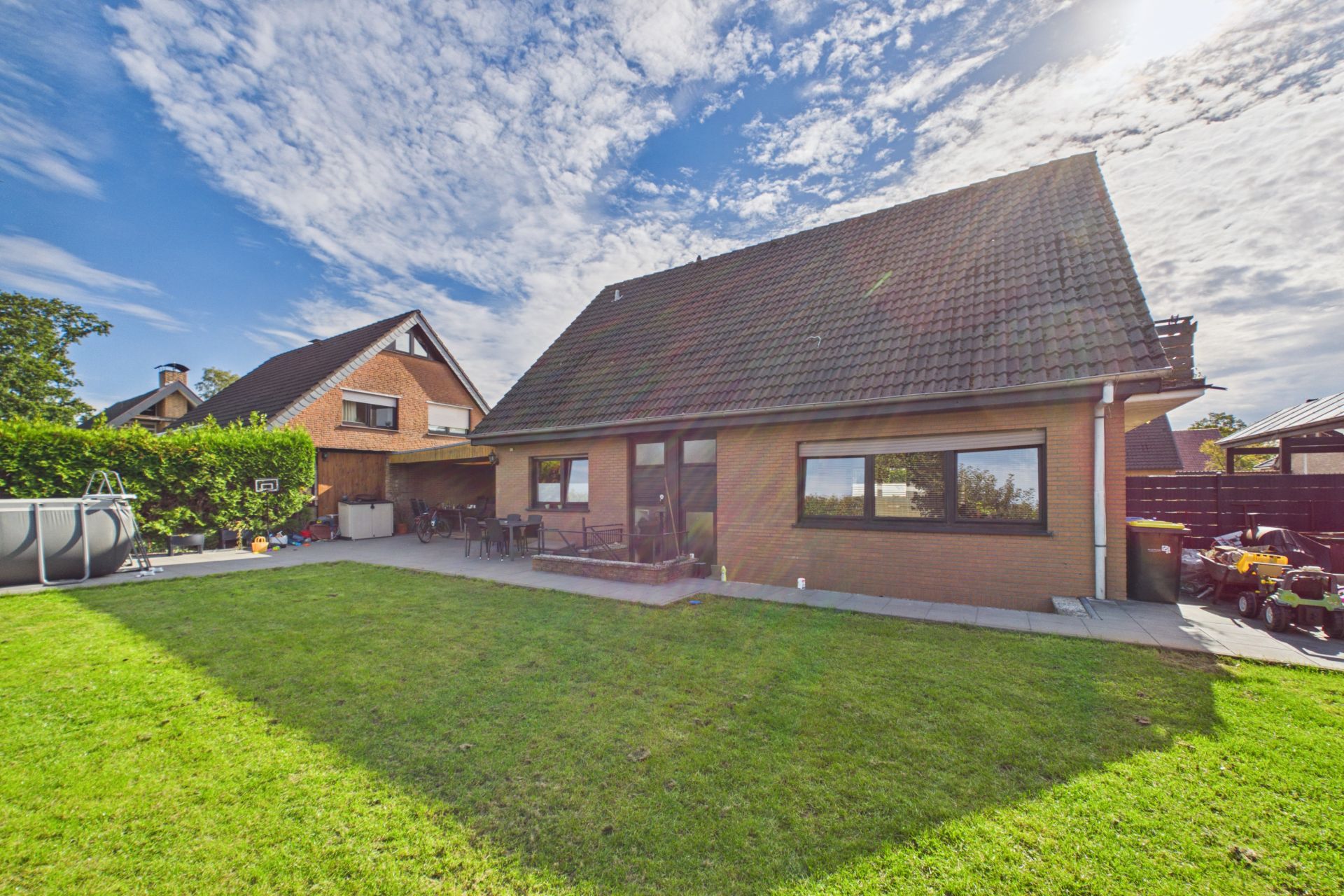 Einfamilienhaus mit großem Garten, Terrasse und aufgestelltem Pool, bei sonnigem Wetter.