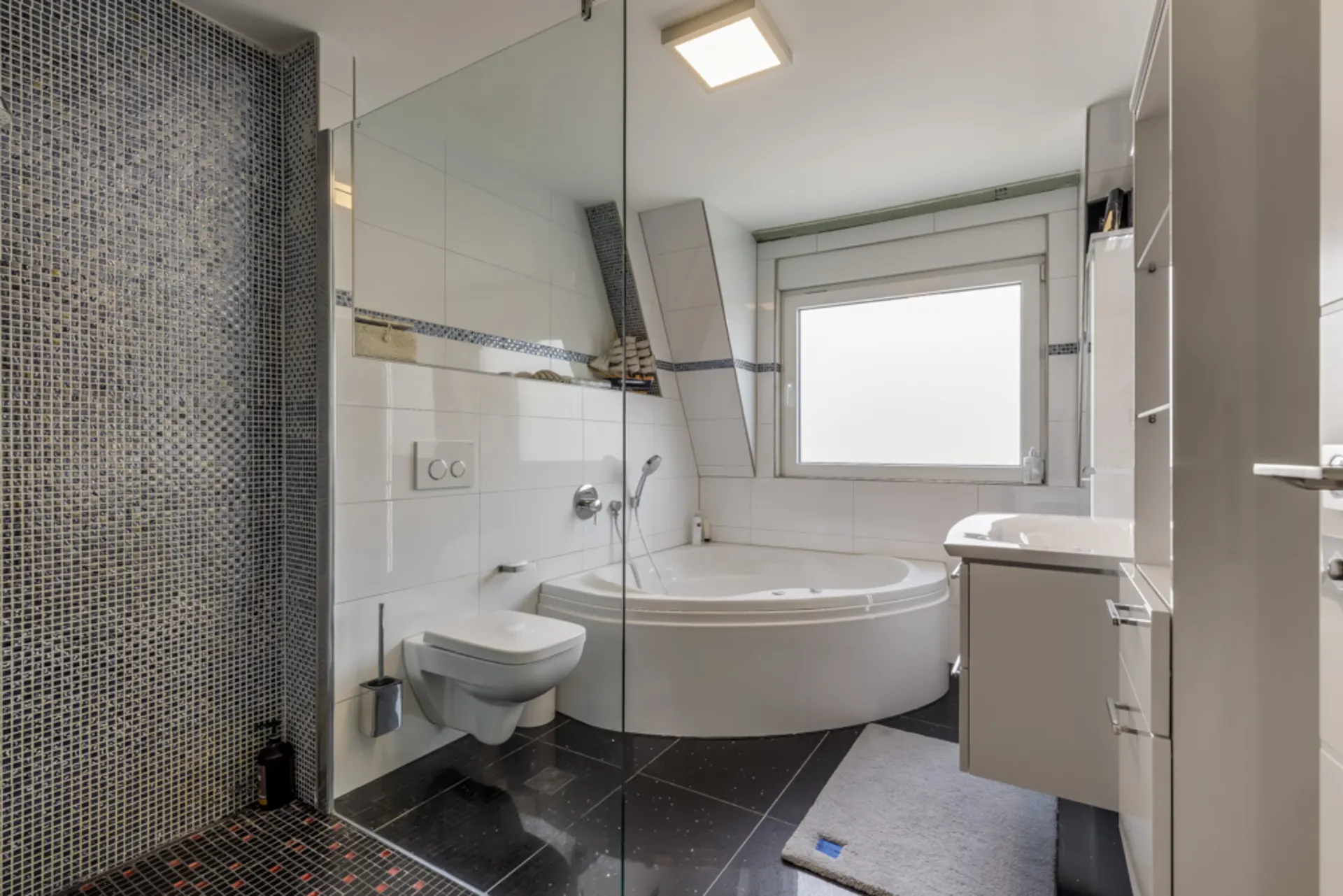 Modernes Badezimmer mit Eckbadewanne, Dusche, WC und großem Fenster.