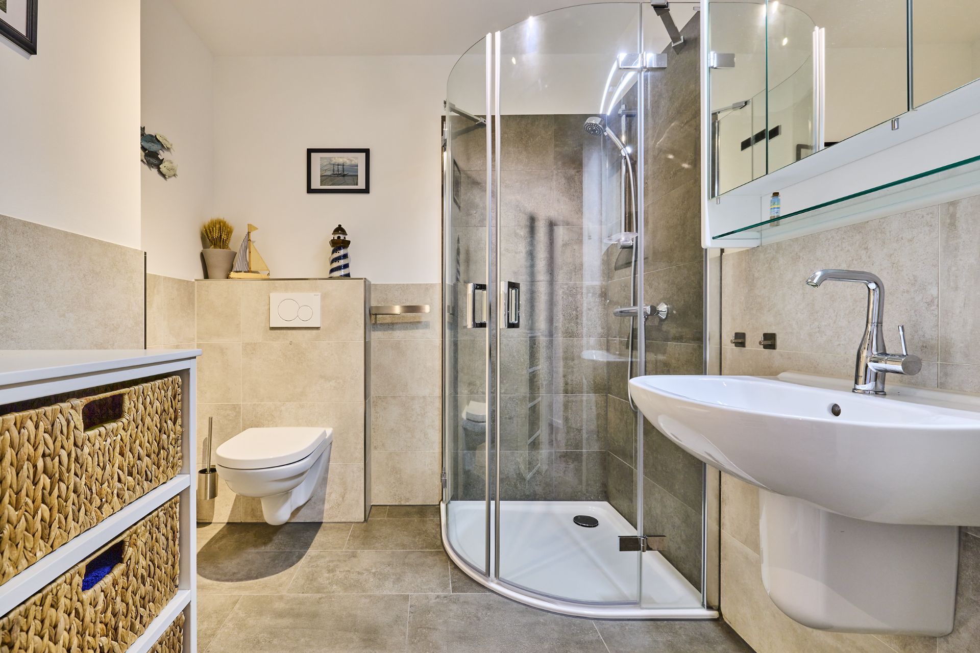 Modernes Badezimmer mit Dusche, Waschbecken, Toilette und Kommode mit Flechtkörben.
