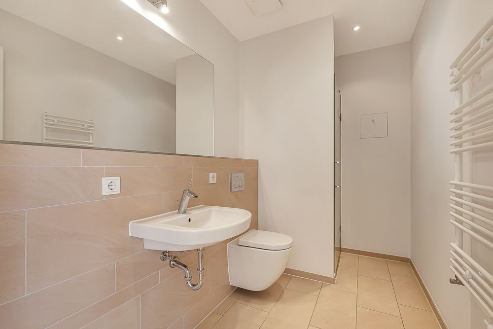 Modernes Badezimmer mit Wandwaschbecken, Hänge-WC, Spiegel und Handtuchheizkörper.