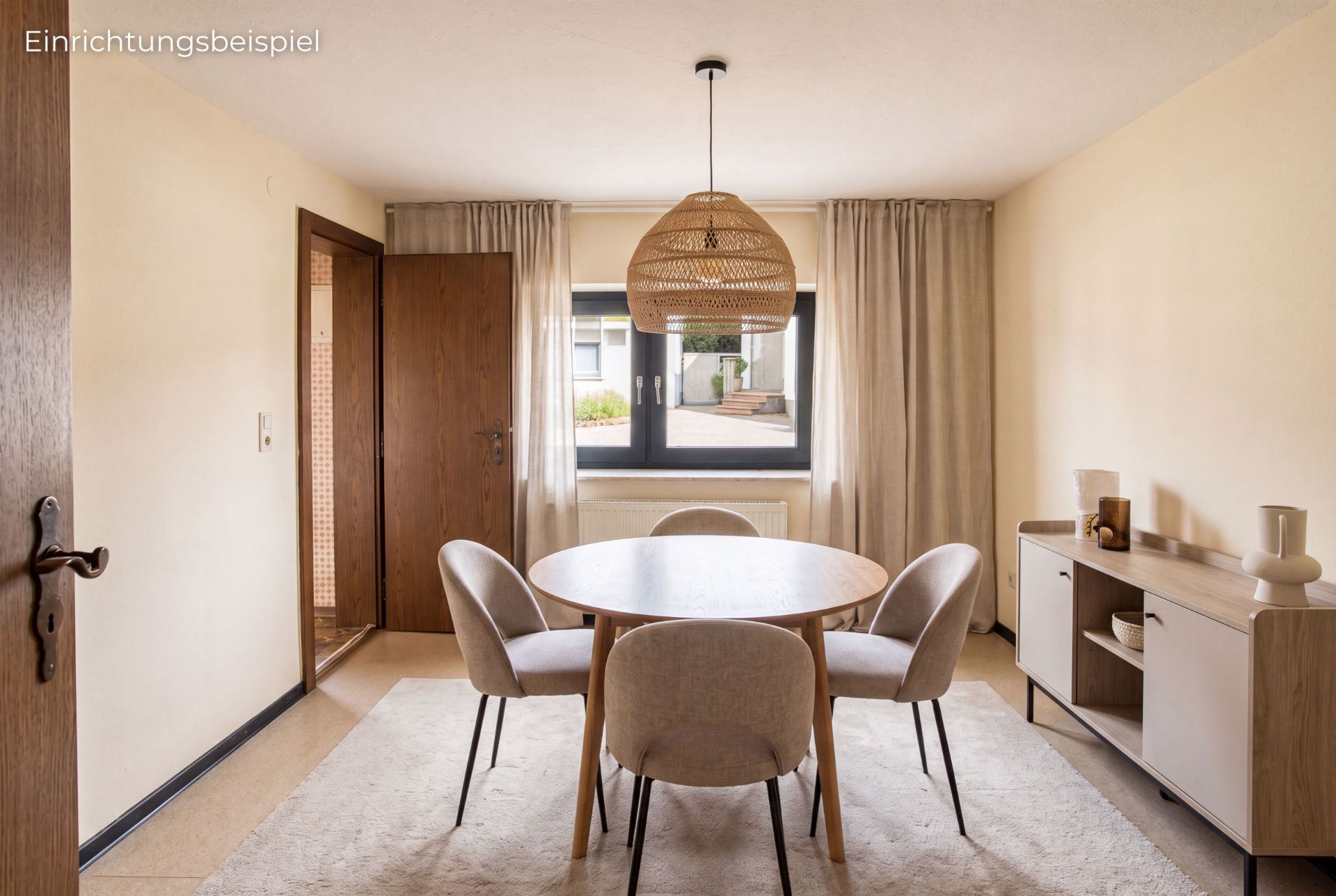 Esszimmer mit rundem Tisch, vier Stühlen, Sideboard und großem Fenster mit Vorhängen.
