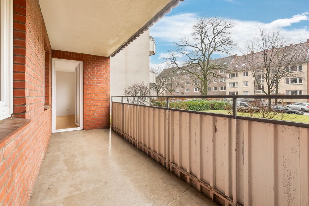 Überdachter Balkon mit Backsteinwänden und Blick auf Wohngebäude und Bäume.