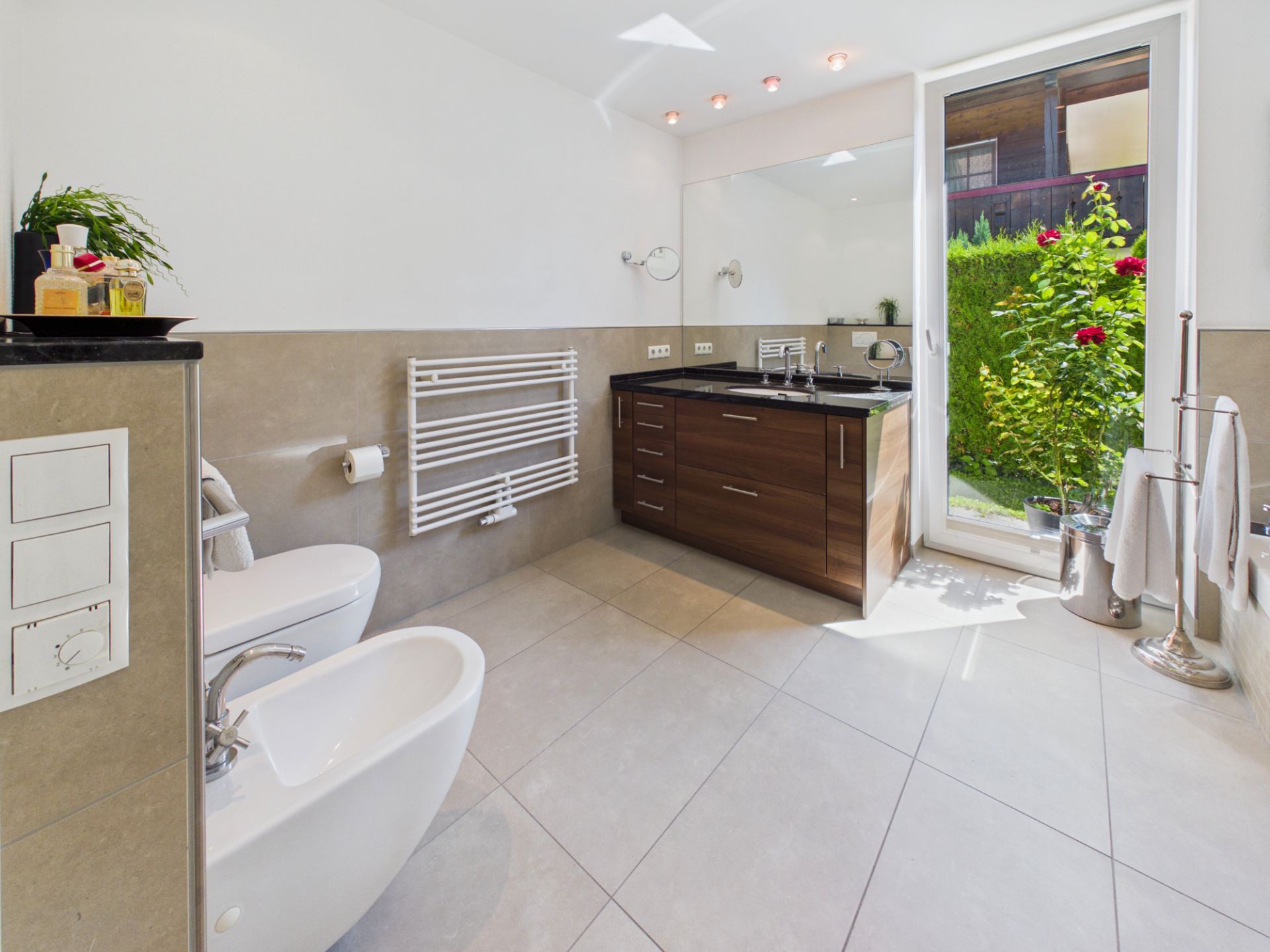 Helles Badezimmer mit Waschbecken, Toilette, Bidet und Tür zum Garten.