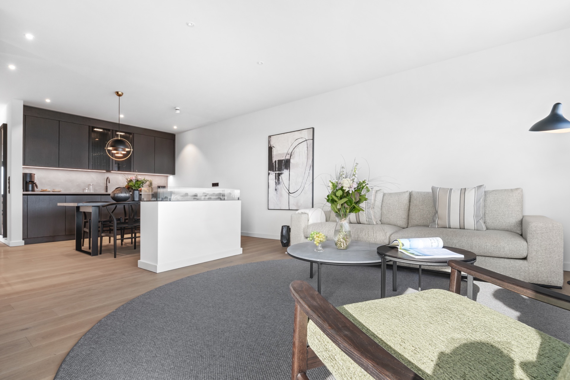 Modernes Wohnzimmer mit Sofa, Couchtisch und offener Küche im Hintergrund.