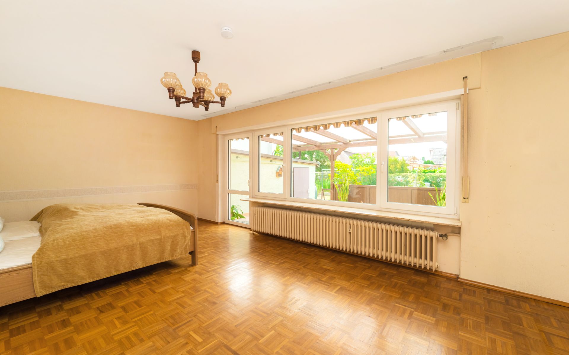 Helles Schlafzimmer mit Holzboden, Bett, großem Fenster und Blick auf eine Terrasse.