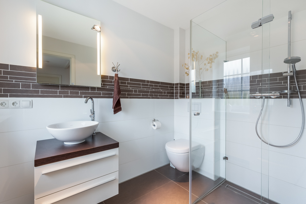 Modernes Badezimmer mit Waschbecken, Spiegel, Toilette und Glasdusche.