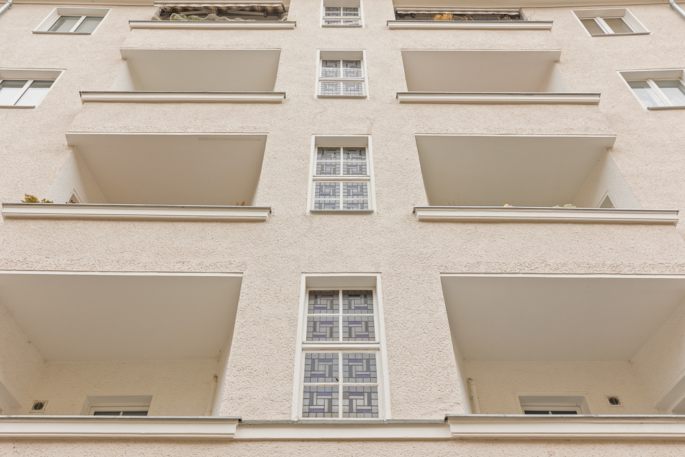 Fassadenansicht eines Mehrfamilienhauses mit mehreren Balkonen und Fenstern.