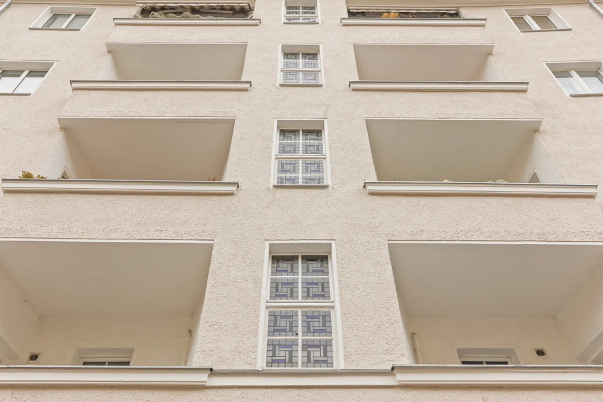 Fassadenansicht eines Mehrfamilienhauses mit mehreren Balkonen und Fenstern.