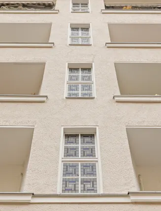 Fassadenansicht eines Mehrfamilienhauses mit mehreren Balkonen und Fenstern.