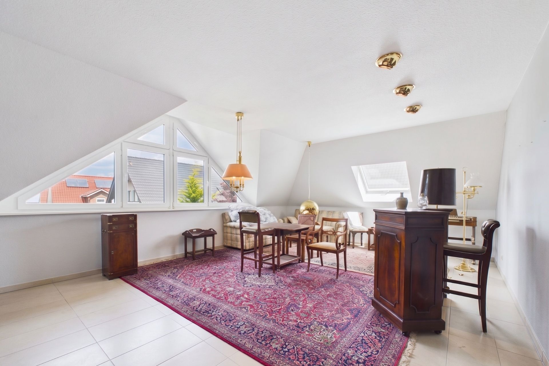 Helles Wohnzimmer mit Dachfenster, roten Teppich und klassischen Holzmöbeln.