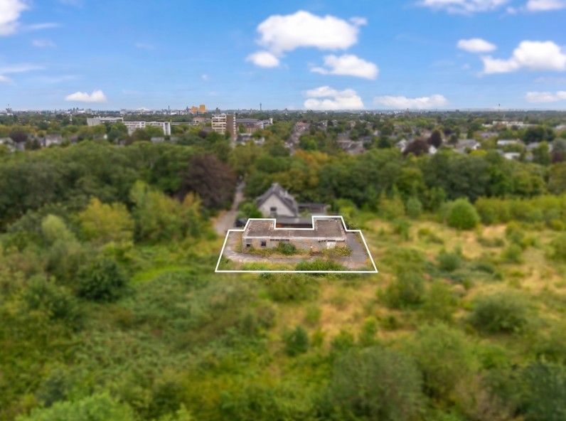 Ein altes Haus steht auf einem umrandeten Grundstück mit viel Grün drumherum.