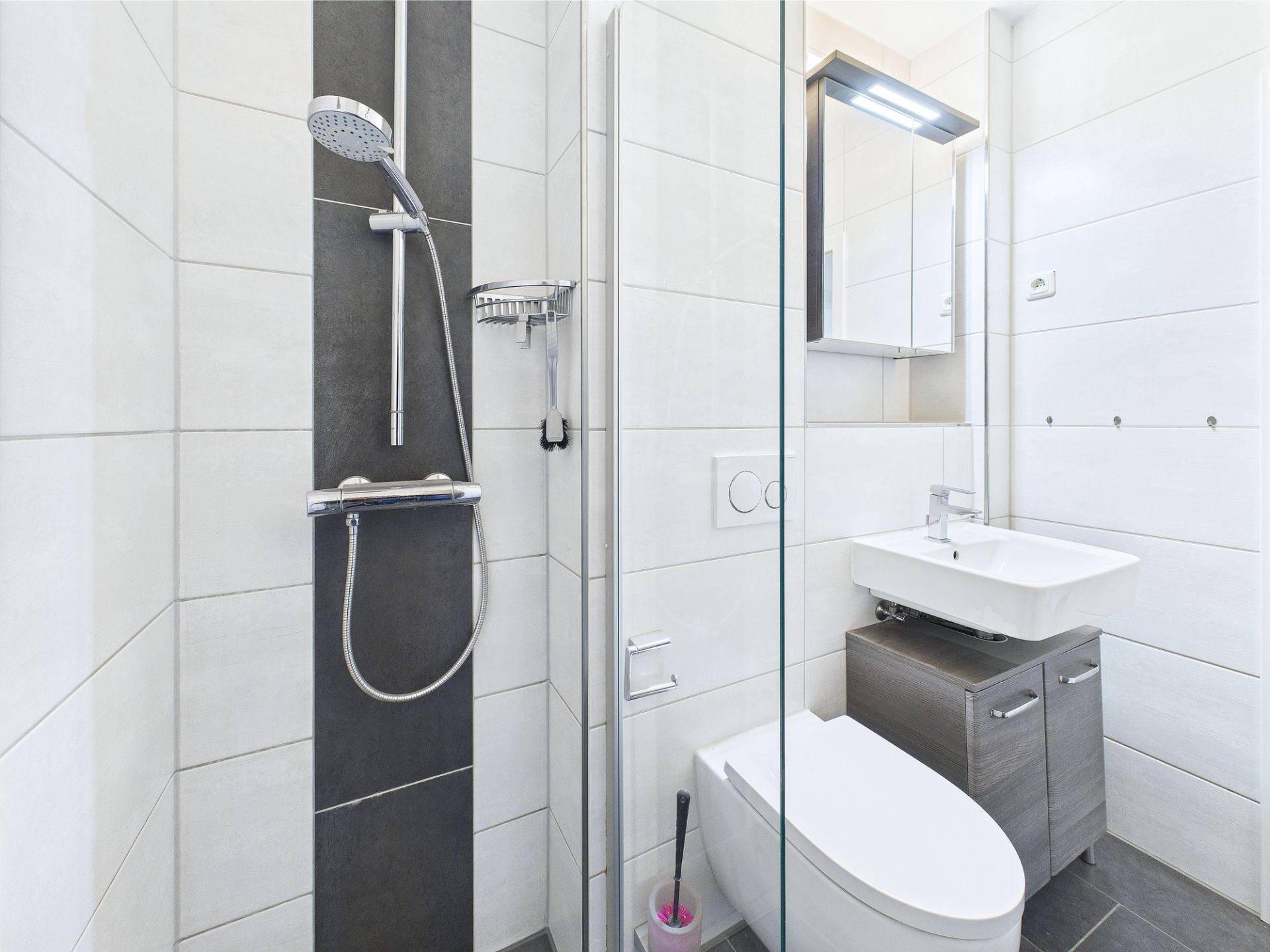 Modernes kleines Bad mit Dusche, WC und Waschbecken mit Spiegel.