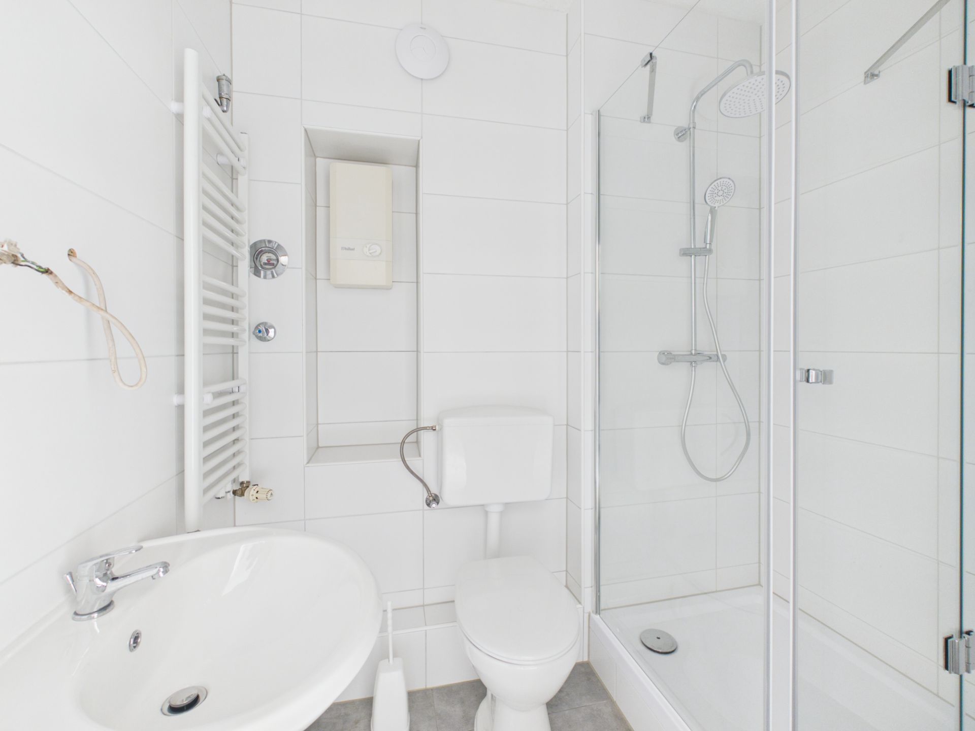 Helles Bad mit Dusche, Toilette, Waschbecken und Handtuchheizung.