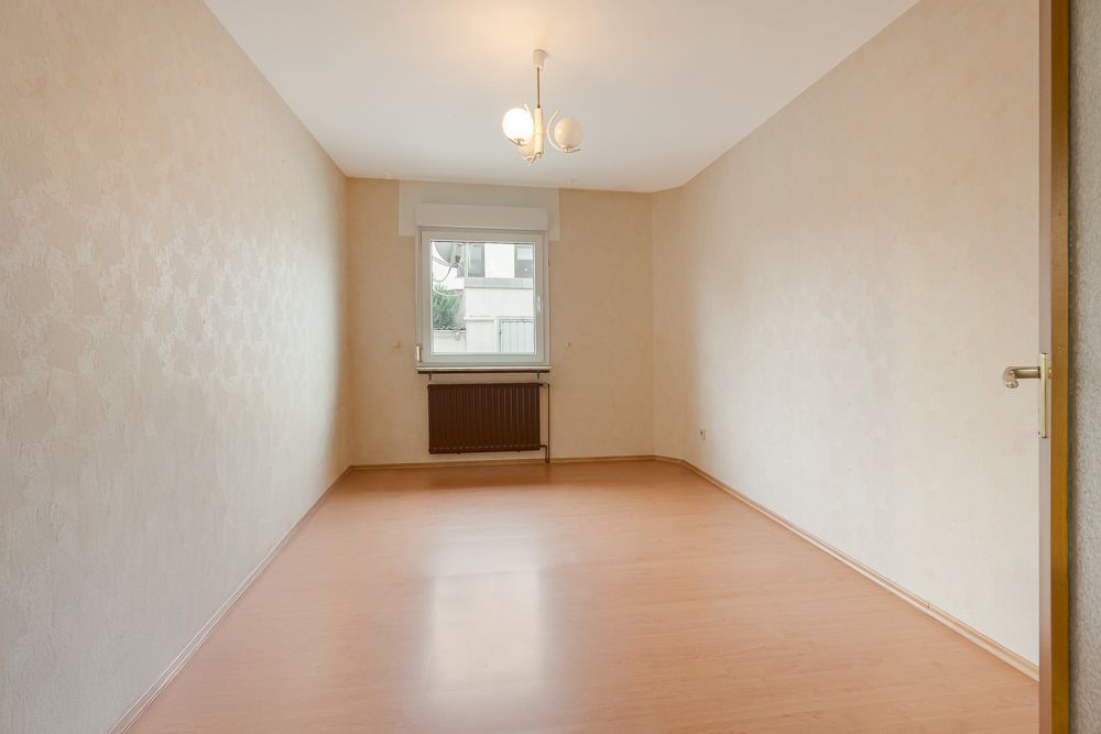 Leerer Raum mit Holzfußboden, Fenster und Deckenlampe.