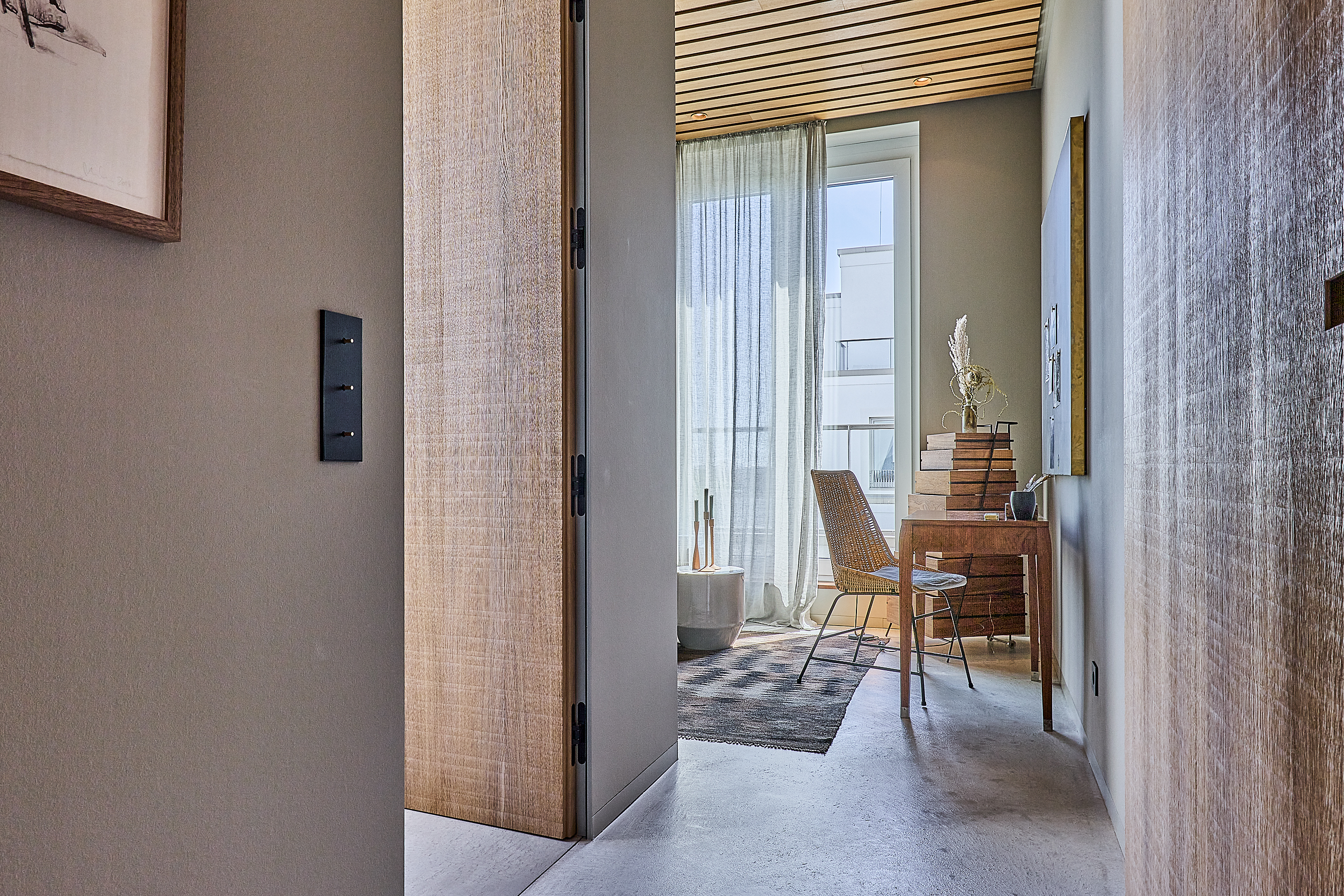 Modernes Zimmer mit Schreibtisch, Stuhl, Teppich und großem Fenster mit Vorhang.