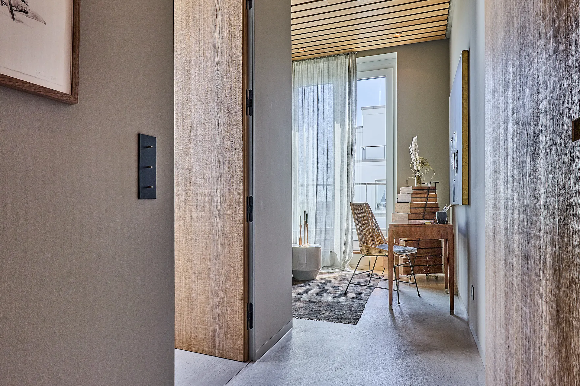 Modernes Zimmer mit Schreibtisch, Stuhl, Teppich und großem Fenster mit Vorhang.