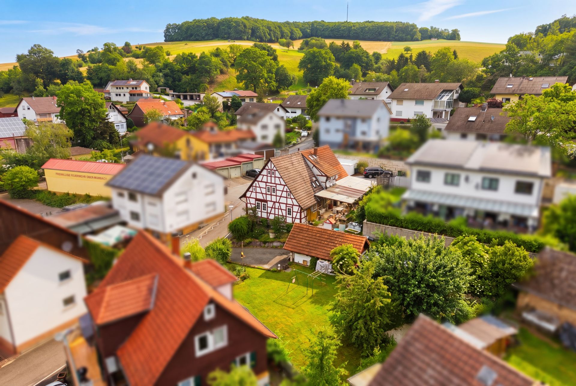 Luftaufnahme eines Wohngebiets mit Fachwerkhaus, Gärten und umliegenden Häusern.