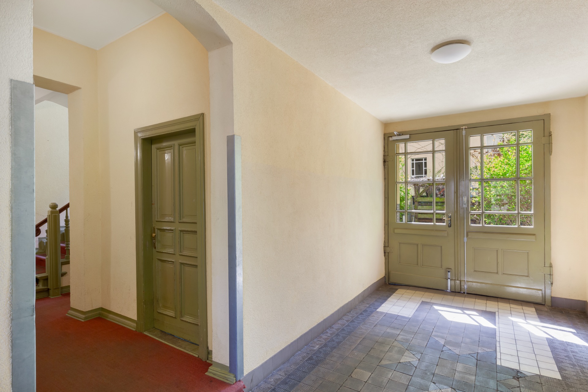 Heller Flur mit Holztür links und doppelter Glastür zum Garten rechts.