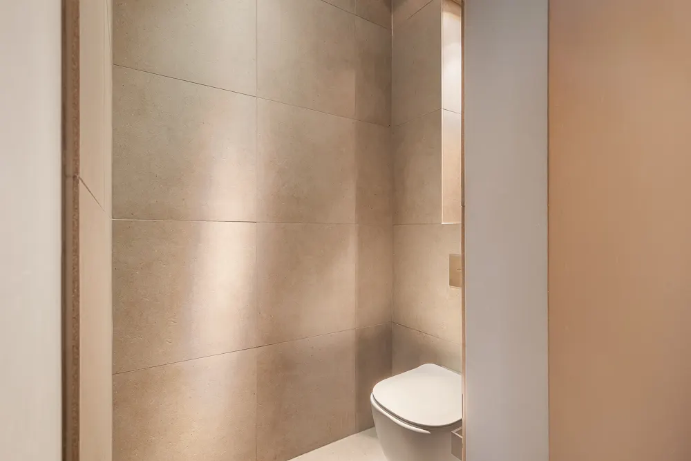 Modernes, kleines WC mit beigen Fliesen und wandhängender Toilette.