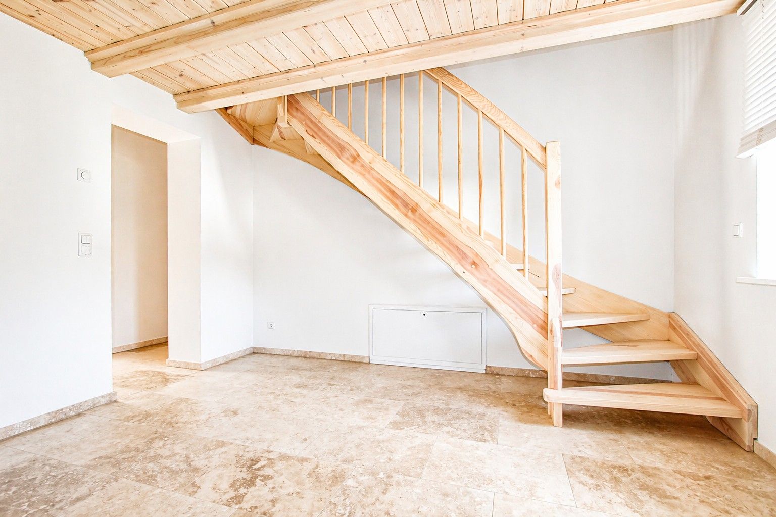 Heller Raum mit Holztreppe und Fliesenboden, Wand und Decke aus hellem Holz.