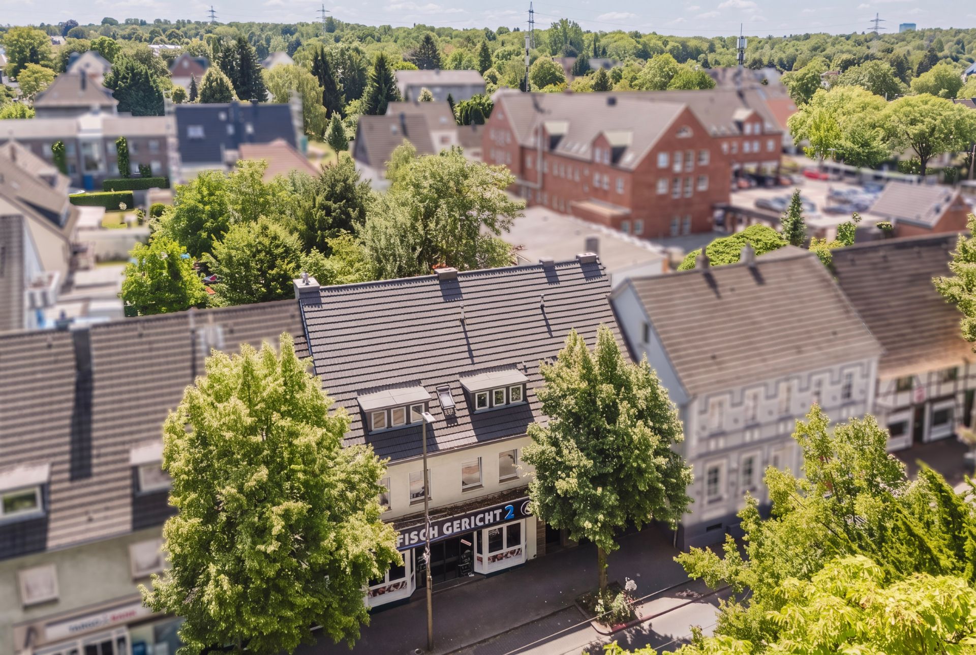 Blick auf eine Häuserreihe mit Bäumen an einer Straße an einem sonnigen Tag.