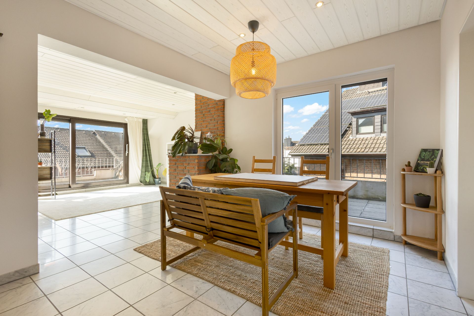 Helles Esszimmer mit Holztisch, Stühlen, Pflanzen und Zugang zu Balkon.