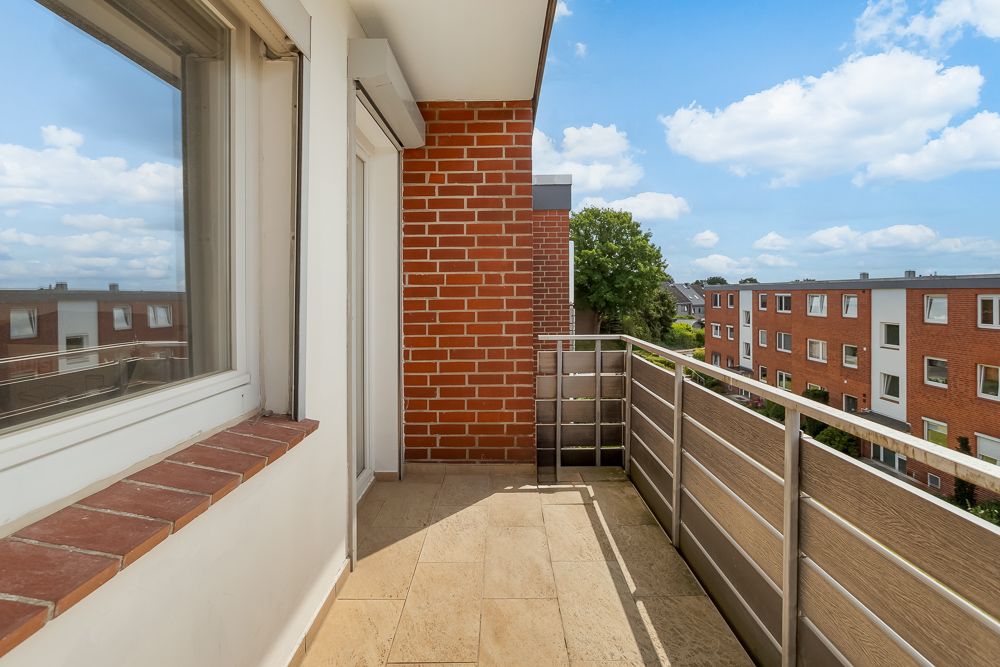 Balkon mit Metallgeländer und Blick auf andere Wohnhäuser bei blauem Himmel.
