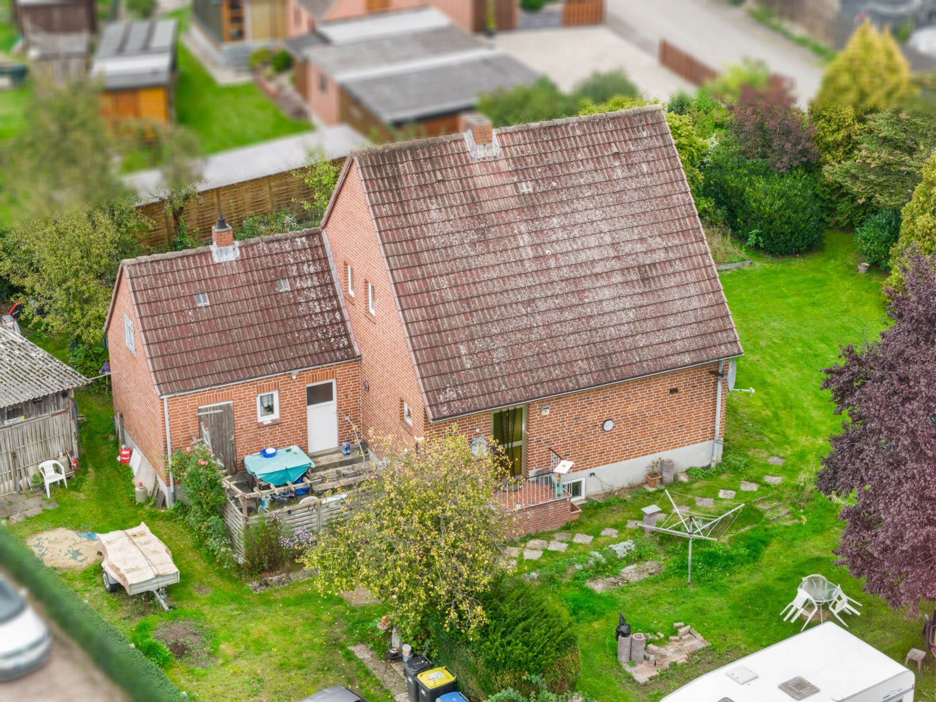 Backstein-Einfamilienhaus mit Garten, Terrasse, Wäscheleine und Gartenmöbeln, aus der Vogelperspektive.
