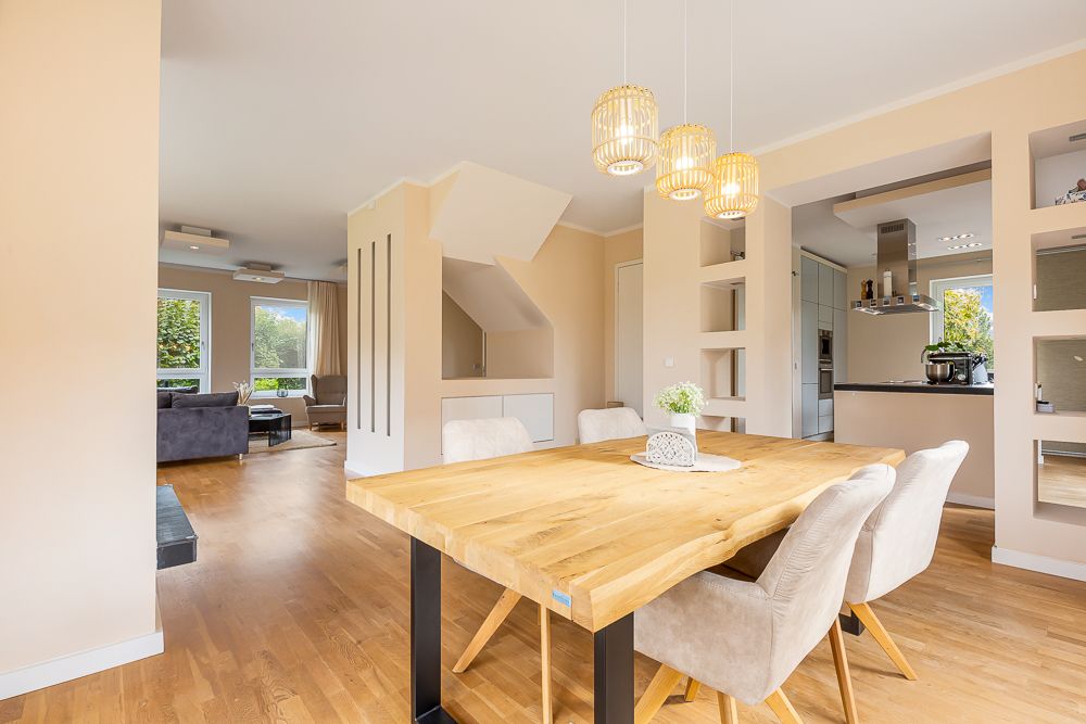 Essbereich mit Holztisch und vier Stühlen, Blick auf Wohnzimmer und Küche, helle Holzböden.