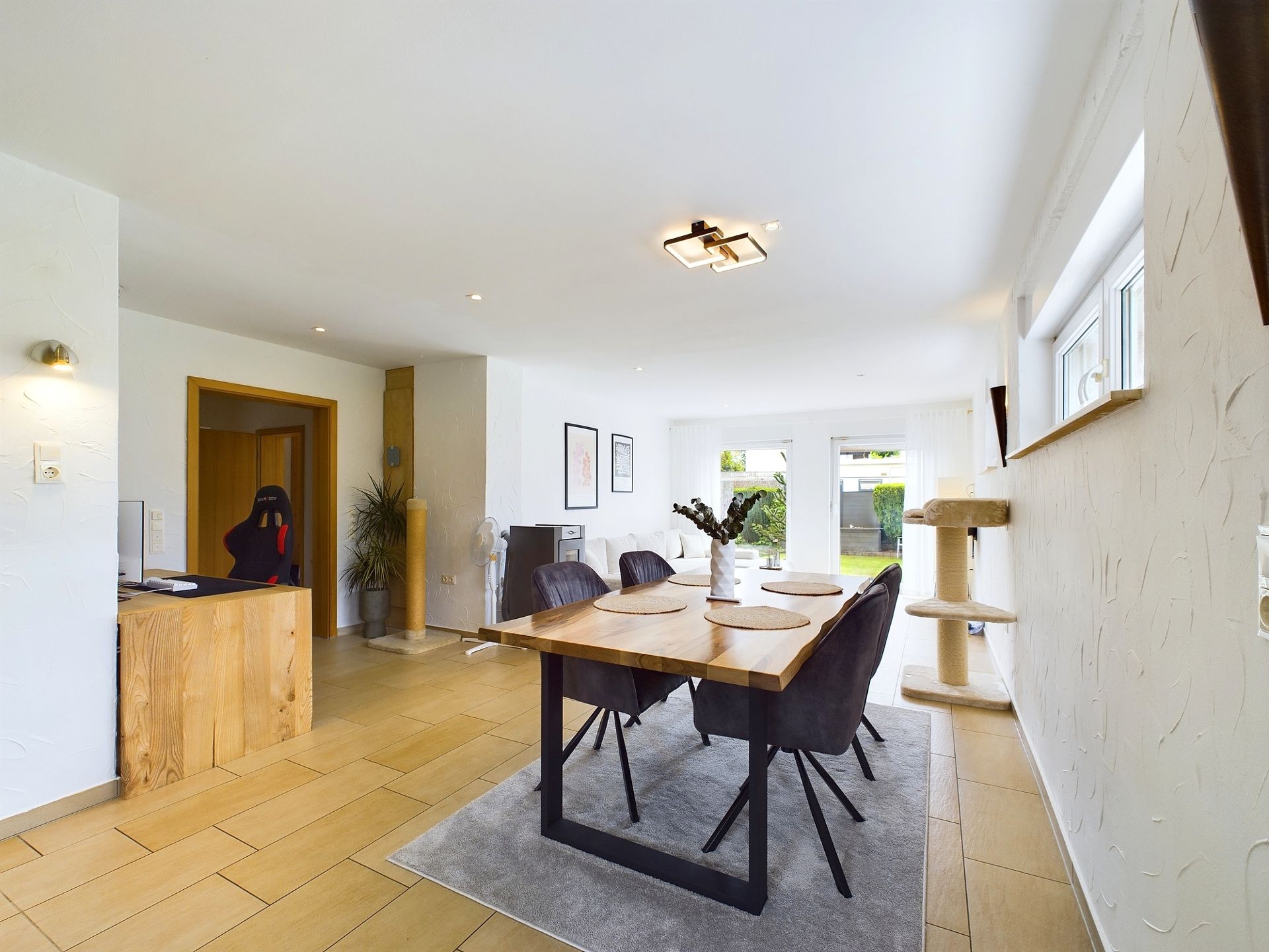 Modernes Esszimmer mit Holztisch, sechs Stühlen und großen Fenstern, helle und offene Gestaltung.
