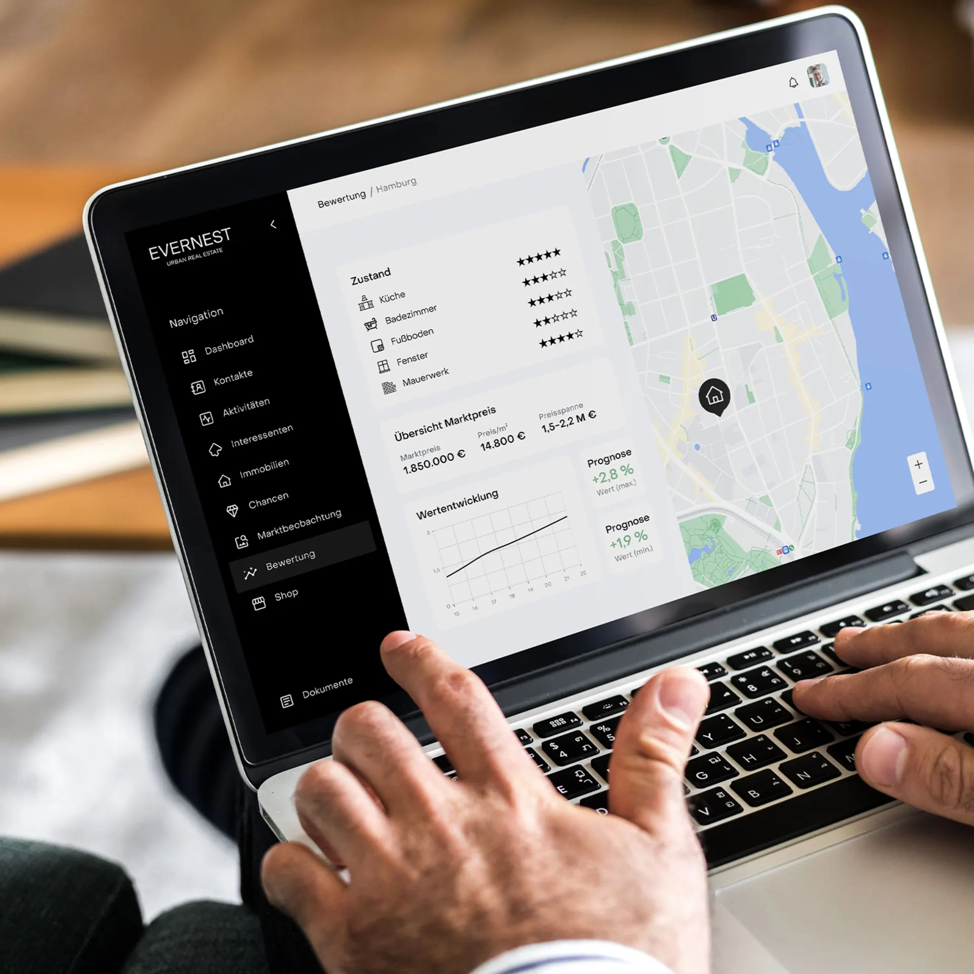 Person benutzt Laptop mit Immobilienbewertungssoftware und Stadtkarte auf dem Bildschirm.