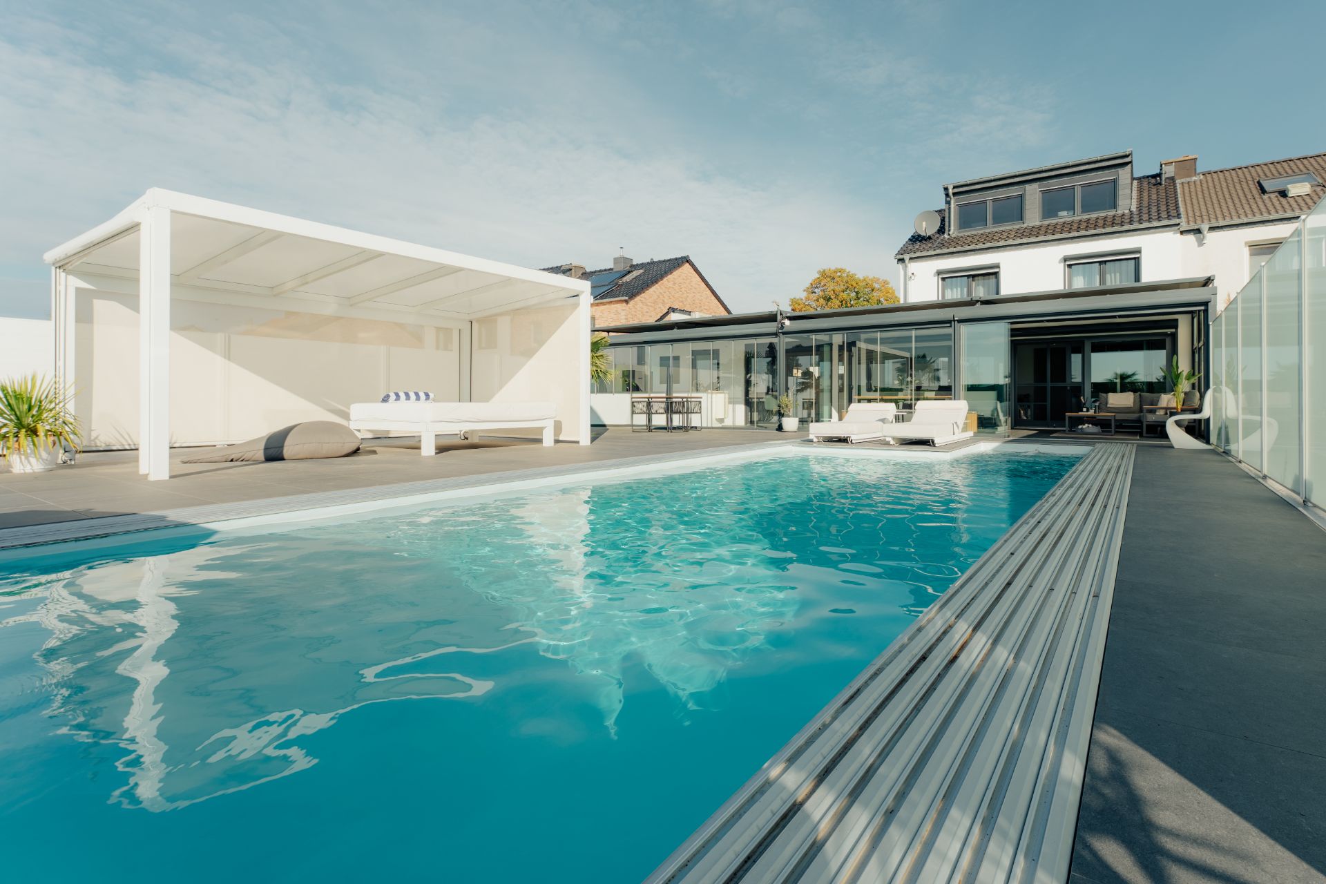 Moderner Wohnhausgarten mit großem Pool, Liegestühlen und überdachtem Sitzbereich.