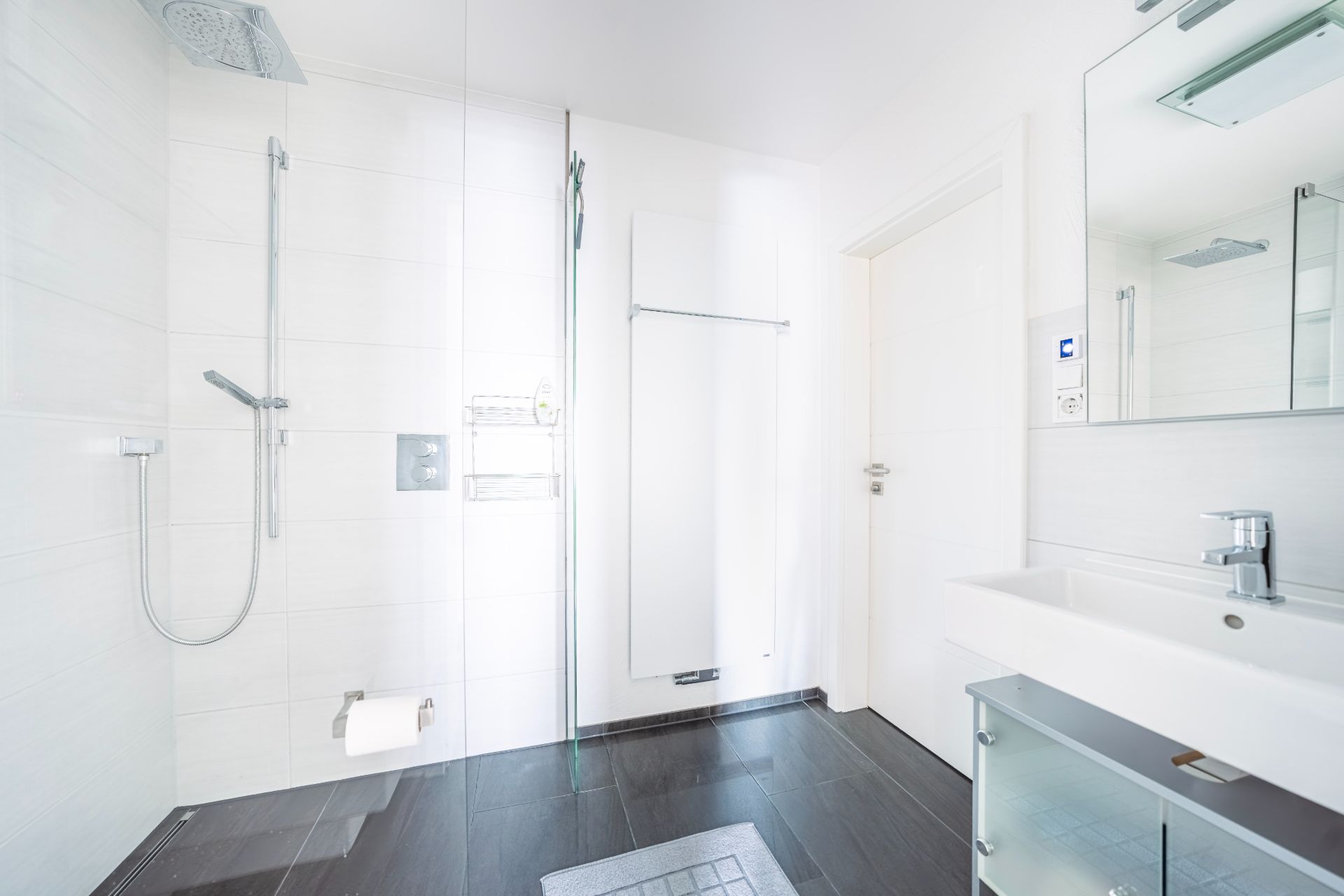 Modernes, weißes Badezimmer mit Dusche, Waschbecken und Spiegel.