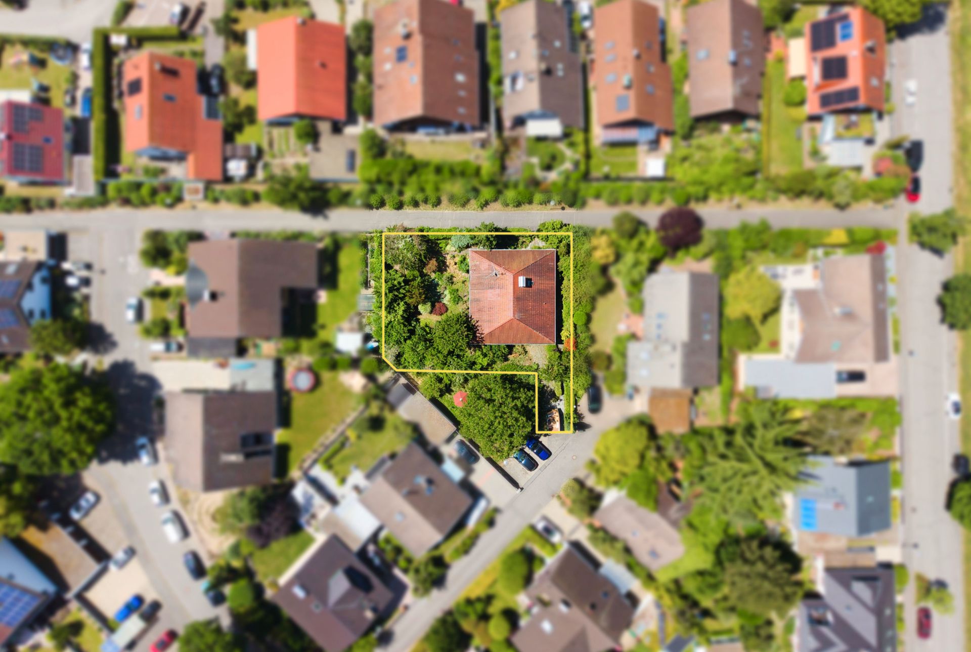 Luftaufnahme eines Hauses mit Garten, von gelben Linien umrahmt, in einem Wohngebiet.