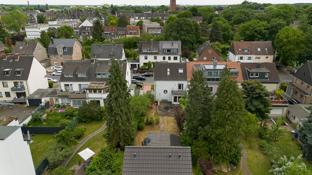 Vogelperspektive auf Wohnhäuser mit Gärten und Bäumen in einer ruhigen Wohngegend.