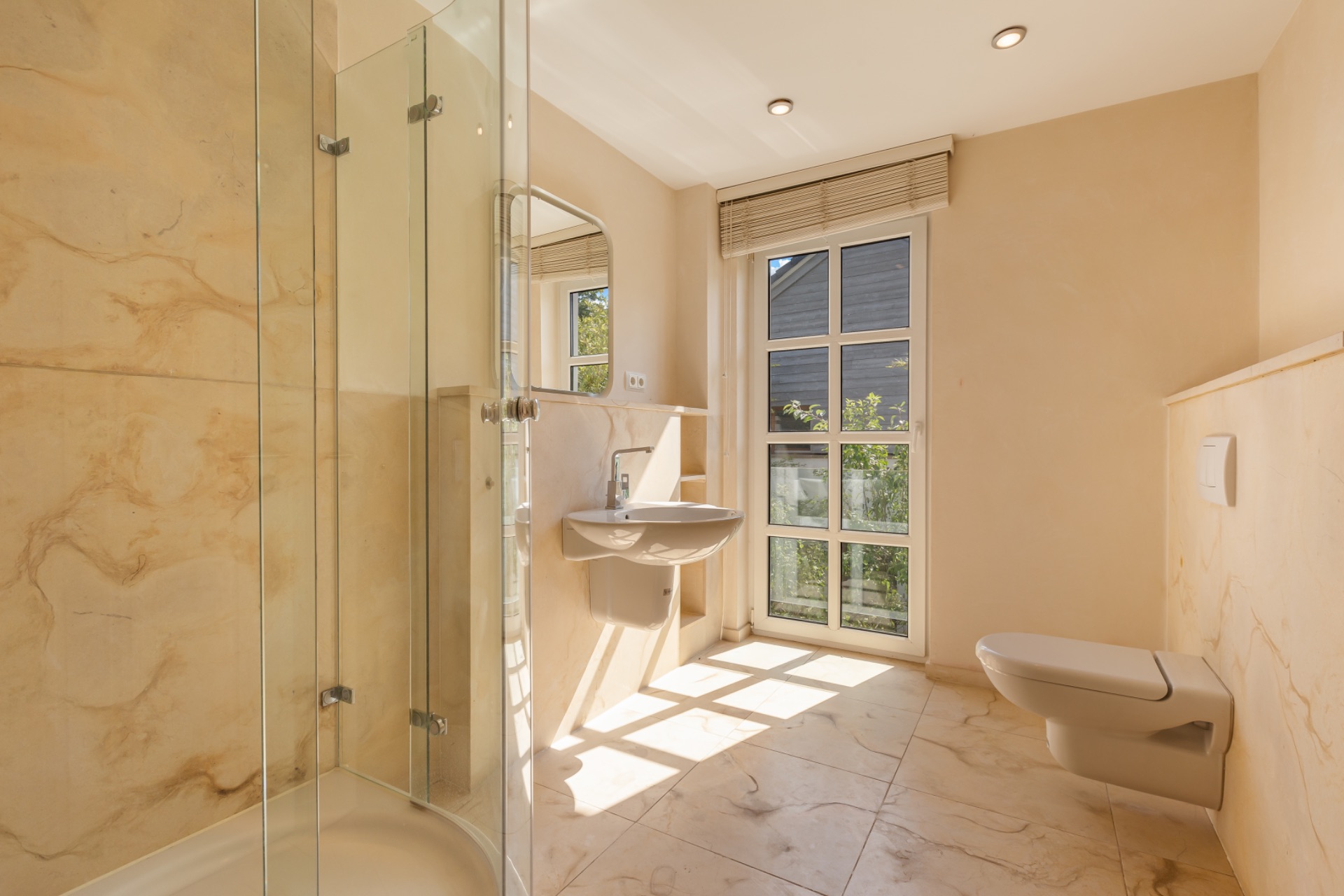 Modernes, helles Badezimmer mit Dusche, Waschbecken, WC und großem Fenster.