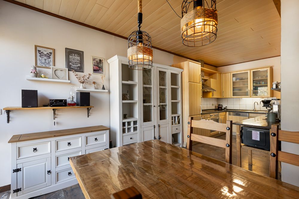 Helle Küche mit Holztisch, weißen Schränken und Regalen an der Wand.