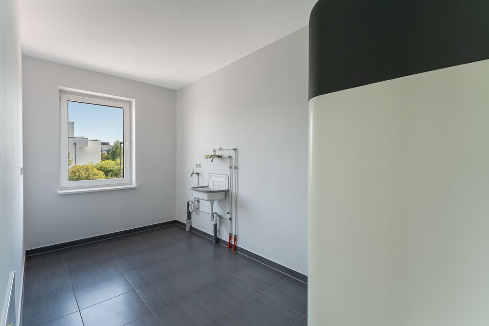 Heller Hauswirtschaftsraum mit Fenster, Waschbecken und großem Gerät im Vordergrund.