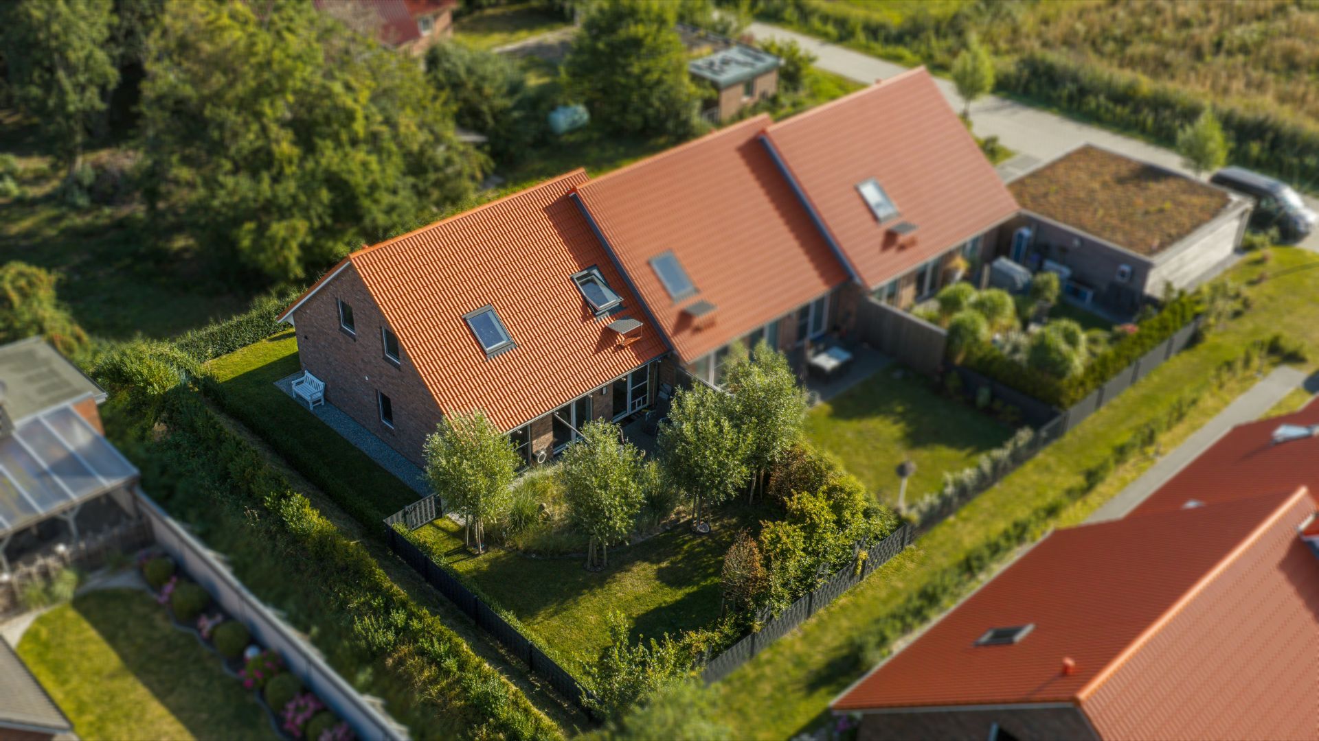 Luftaufnahme von zwei nebeneinanderliegenden Häusern mit roten Dächern und Gärten.