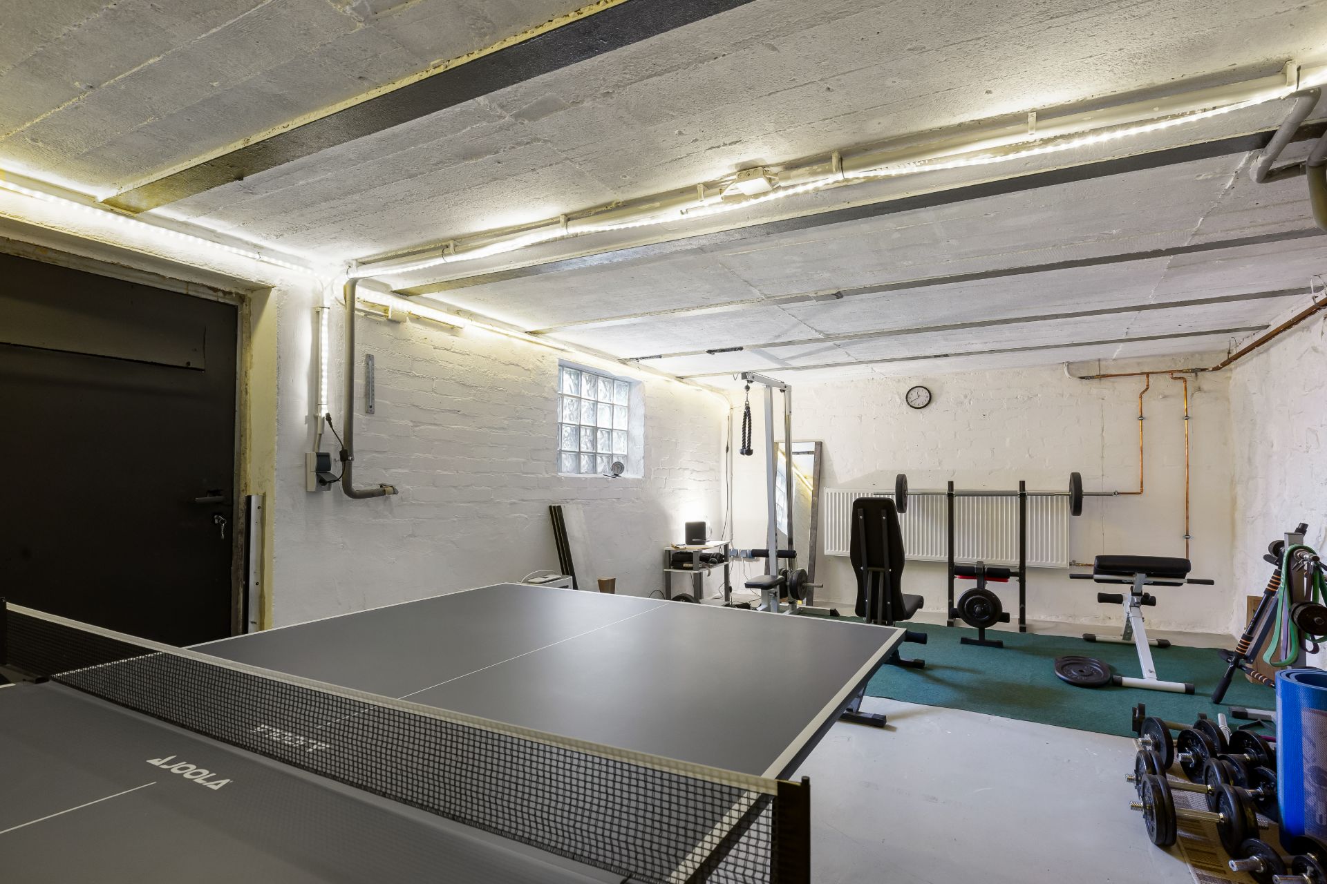 Kellerraum mit Tischtennisplatte und Fitnessgeräten.