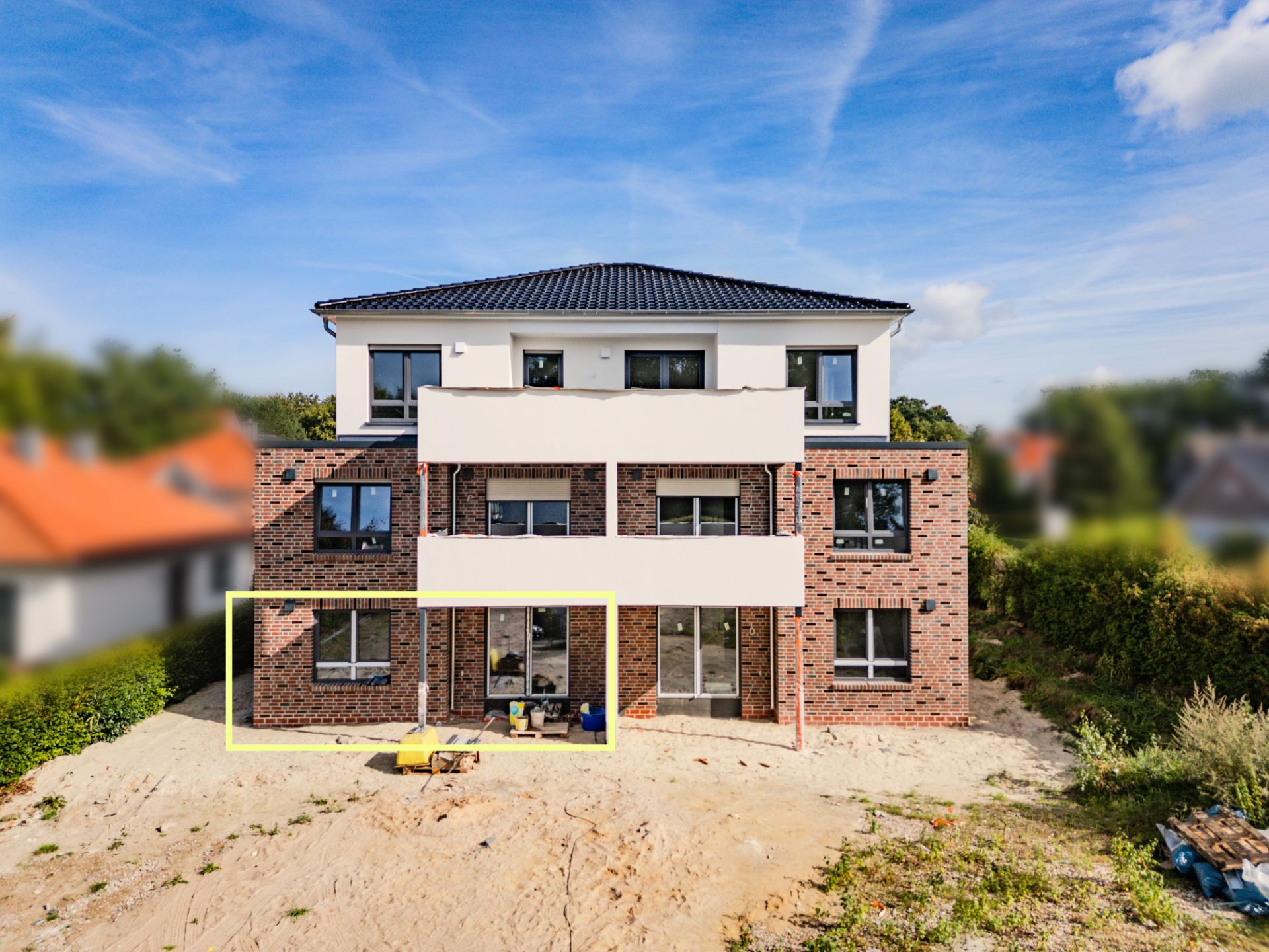 Neues zweistöckiges Wohnhaus mit Garten, gelber Rahmen um Erdgeschossbereich.