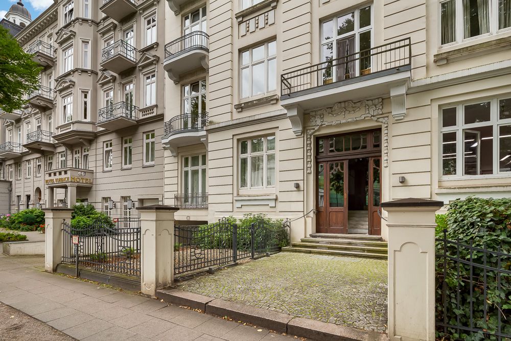 Großes, mehrstöckiges Wohnhaus mit Balkonen, Fenstern und Eingangstreppe mit Tor.