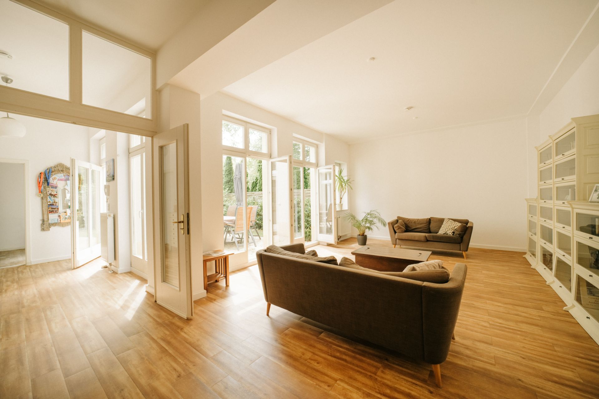 Helles Wohnzimmer mit zwei Sofas, Couchtisch, Regalwand und großen Fenstern zum Garten.