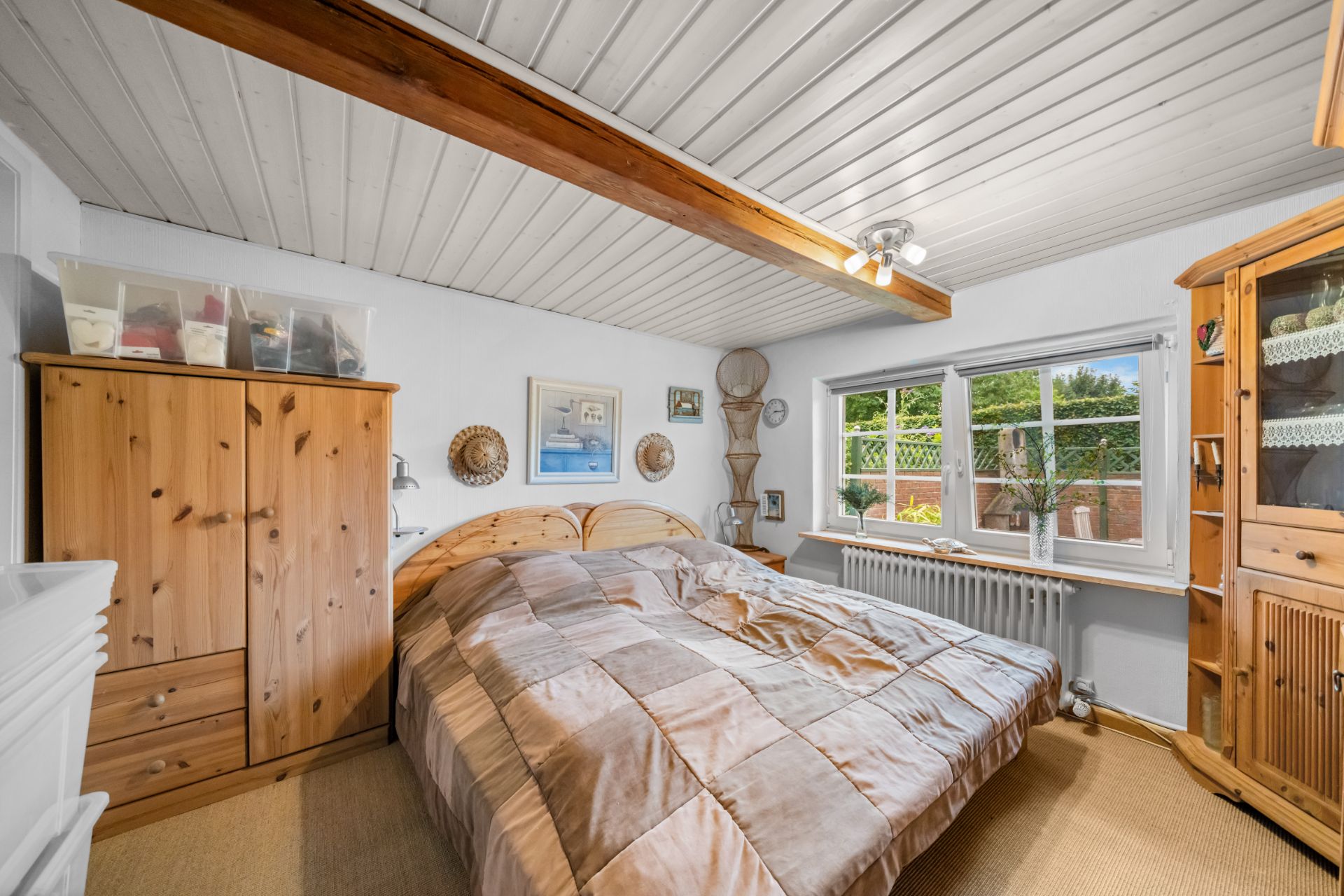 Schlafzimmer mit Holzmöbeln, Doppelbett und großem Fenster mit Blick nach draußen.