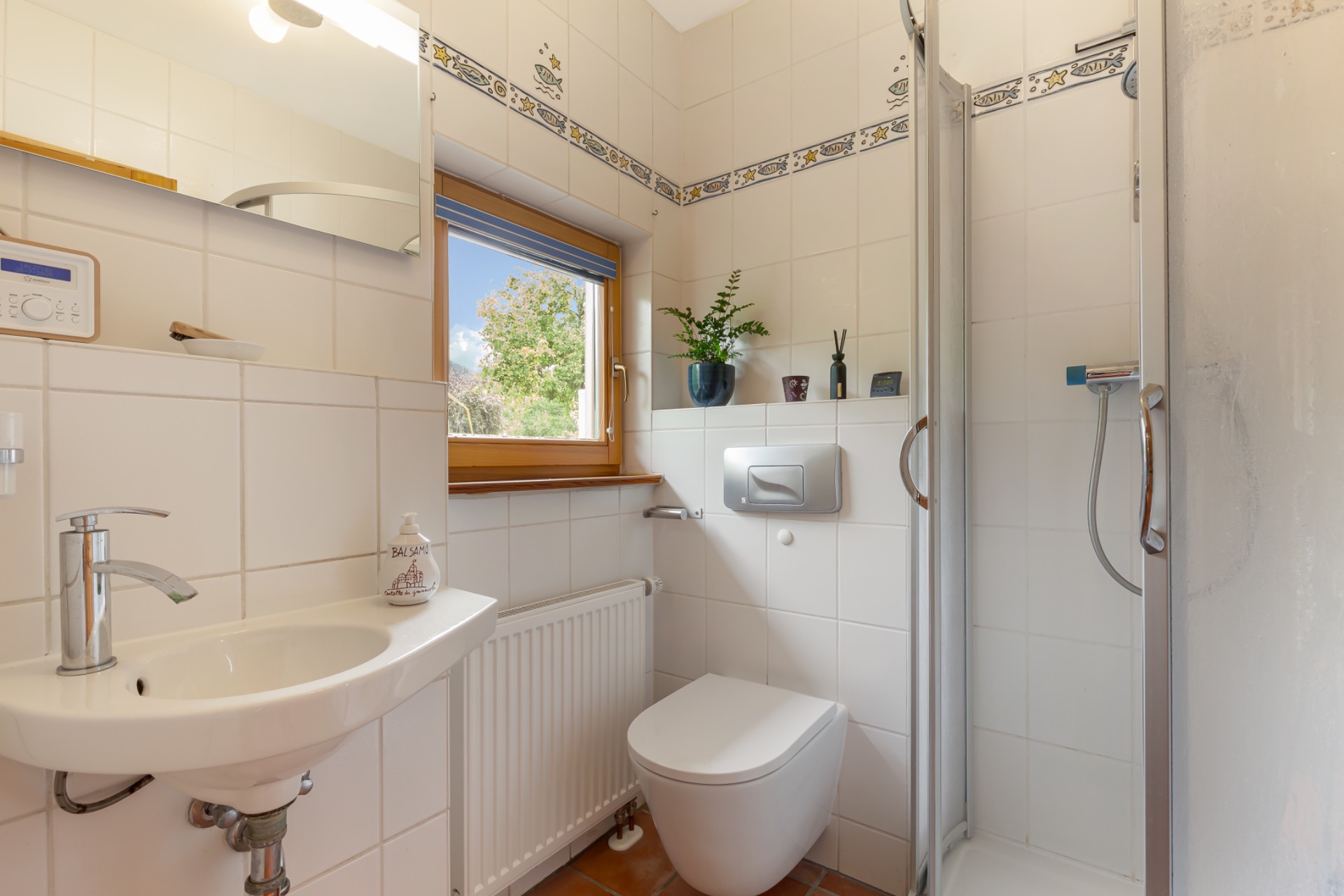 Kleines Badezimmer mit Waschbecken, Toilette, Dusche und Fenster.