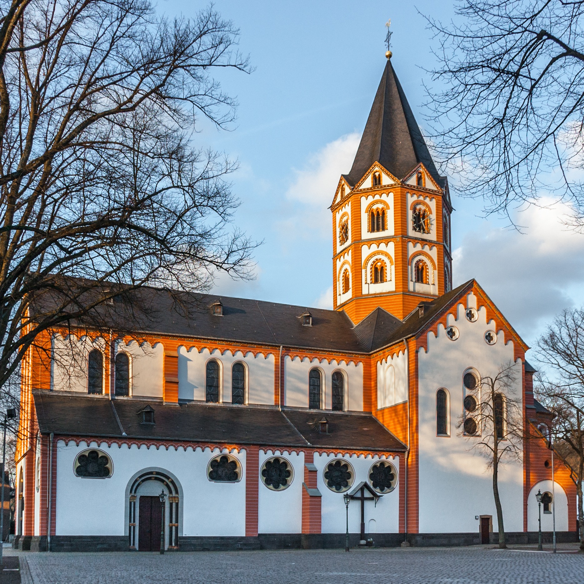Stadtpanorama mit Kirche, historischen Gebäuden und Schiffen am Flussufer bei sonnigem Wetter.