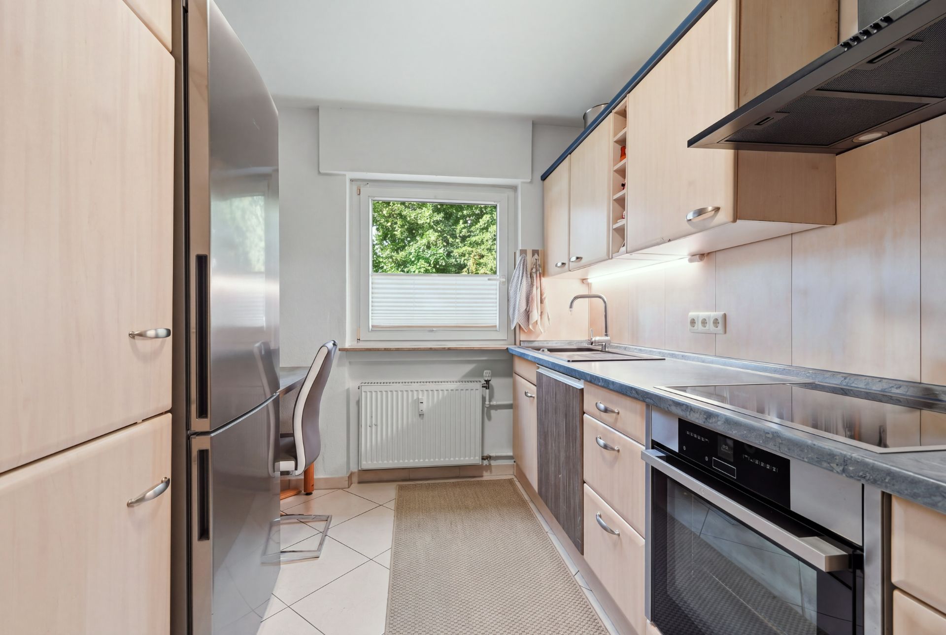Moderne Einbauküche mit großem Kühlschrank, Fenster, Herd und Spüle.
